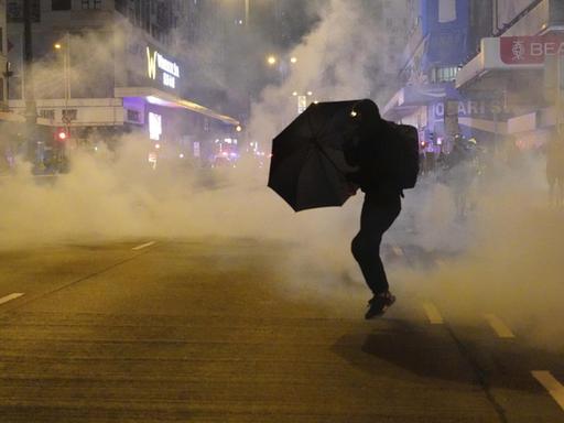 Ein regierungskritischer Demonstrant schützt sich mit einem Regenschirm vor Tränengas.