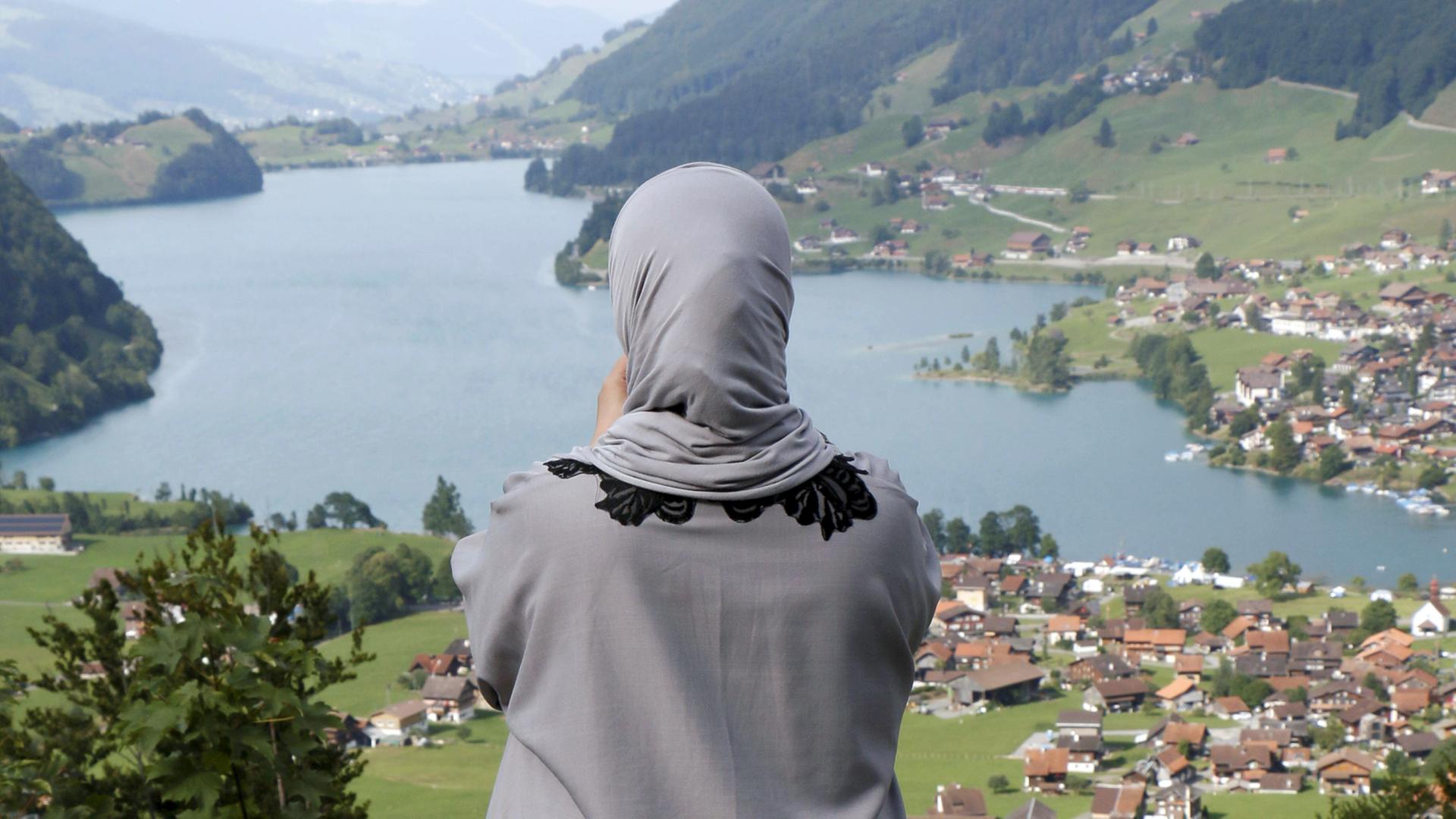 Eine Muslimin mit Kopftuch schaut auf den Lungernsee im Kanton Obwalden in der Schweiz. Eine Muslimin mit Kopftuch schaut auf den Lungernsee im Kanton Obwalden in der Schweiz.