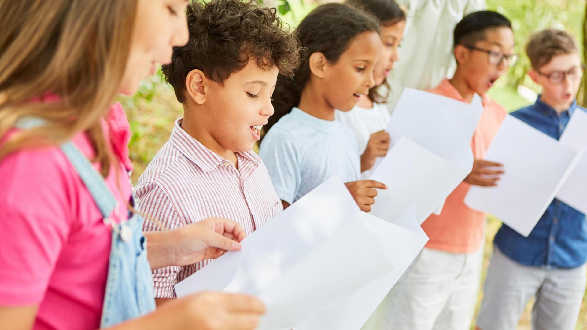 Kinder halten Notenblätter und singen Kinder halten Notenblätter und singen