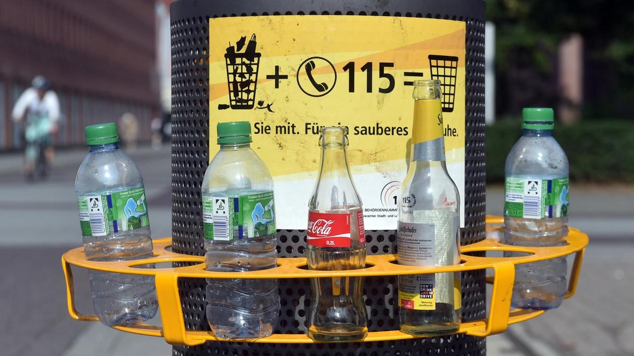 ILLUSTRATION _ An einem Mülleimer in der Innenstadt von Karlsruhe (Baden-Württemberg) ist am 06.08.2014 ein Pfandring angebracht in dem leere Flaschen stehen. Wer seine Pfandflaschen oder -dosen nicht ins Geschäft zurückbringen möchte, kann sie in die Ringe stecken. So ist es Pfandsammlern einfacher möglich, die Flaschen und Dosen mitzunehmen. Sie müssen nicht mehr in die Abfallbehälter hineingreifen und den Müll durchwühlen. 