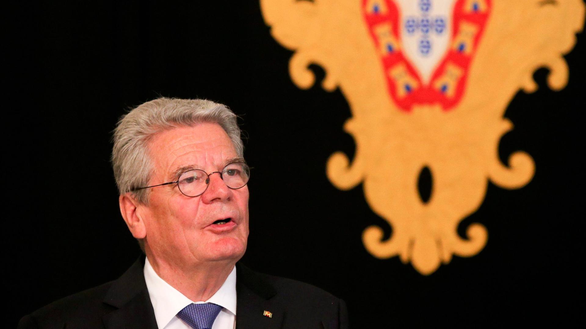 Joachim Gauck hält vor einem Wappen vor schwarzem Hintergrund eine Rede Joachim Gauck hält vor einem Wappen vor schwarzem Hintergrund eine Rede