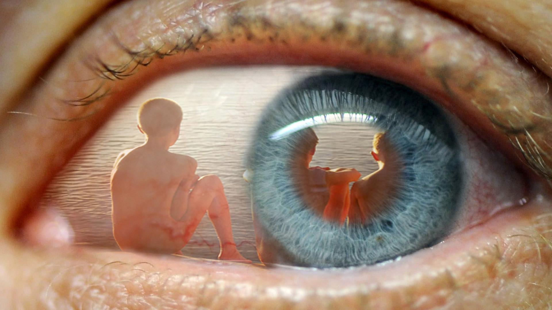 In einem Auge spiegelt sich das Bild von Kindern am Strand. In einem Auge spiegelt sich das Bild von Kindern am Strand.