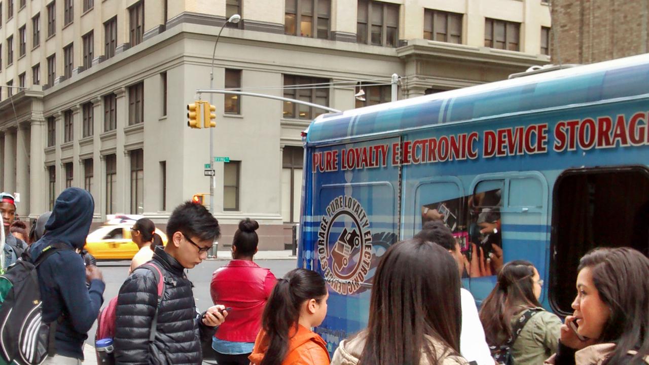 Schüler geben vor einer Schule in New York City ihre Telefone ab. Schüler geben vor einer Schule in New York City ihre Telefone ab.