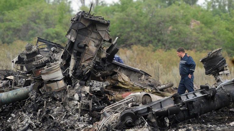 Ein Helfer steht in den vollkommen zerstörten Trümmerteilen der Malaysia-Airlines-Maschine in der Ost-Ukraine Ein Helfer steht in den vollkommen zerstörten Trümmerteilen der Malaysia-Airlines-Maschine in der Ost-Ukraine