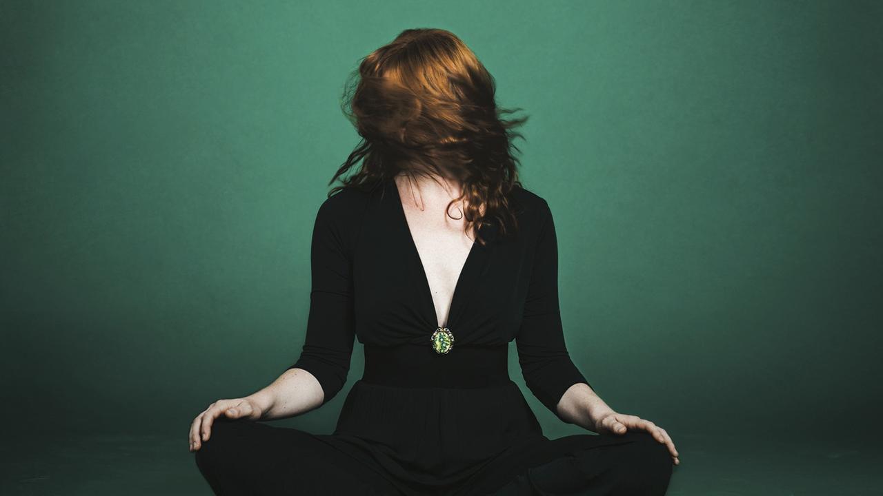 Albumcover: Ein Frau sitzt vor grünem Hintergrund und versteckt ihr Gesicht hinter ihren roten Haaren.