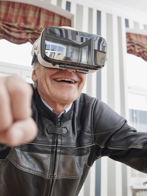 Ein älterer Mann in einer Motorradjacke trägt eine VR-Brille.