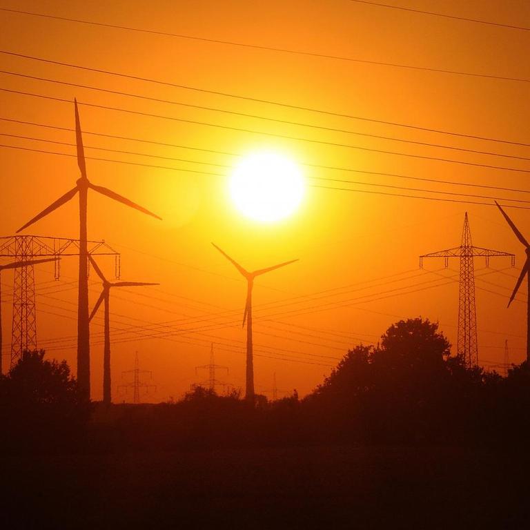 Das Foto zeigt die Abendsonne hinter dem Windpark am Stadtrand von Nauen (Brandenburg).