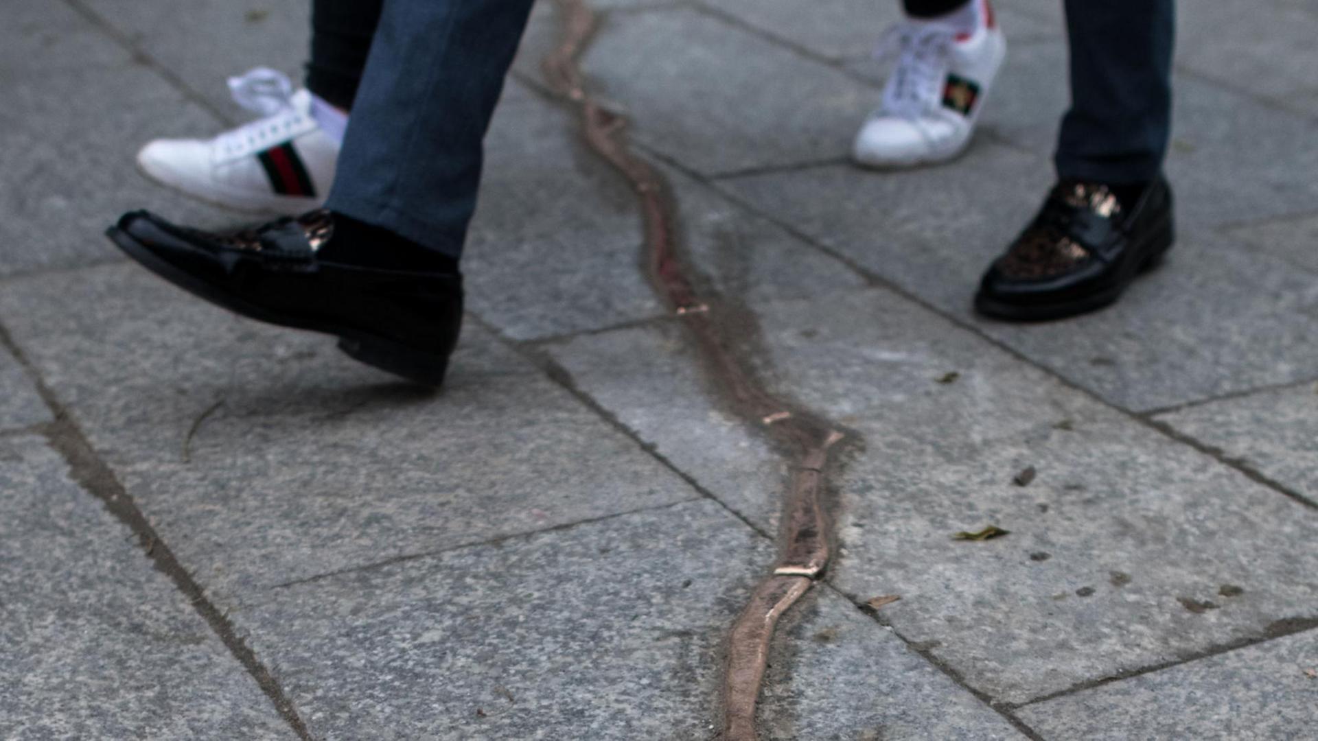 Passanten gehen am 24.11.2017 über einen aus Bronze nachempfundenen Riss in den Bodenplatten auf dem Weihnachtsmarkt an der Gedächtniskirche in Berlin. Passanten gehen am 24.11.2017 über einen aus Bronze nachempfundenen Riss in den Bodenplatten auf dem Weihnachtsmarkt an der Gedächtniskirche in Berlin.