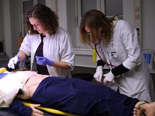 Die Medizinstudenten Marie (l) und Helene führen in der Charité in Berlin bei der Übung "Simulierte Rettungsstelle" eine Notfallbehandlung an einem Dummy durch.