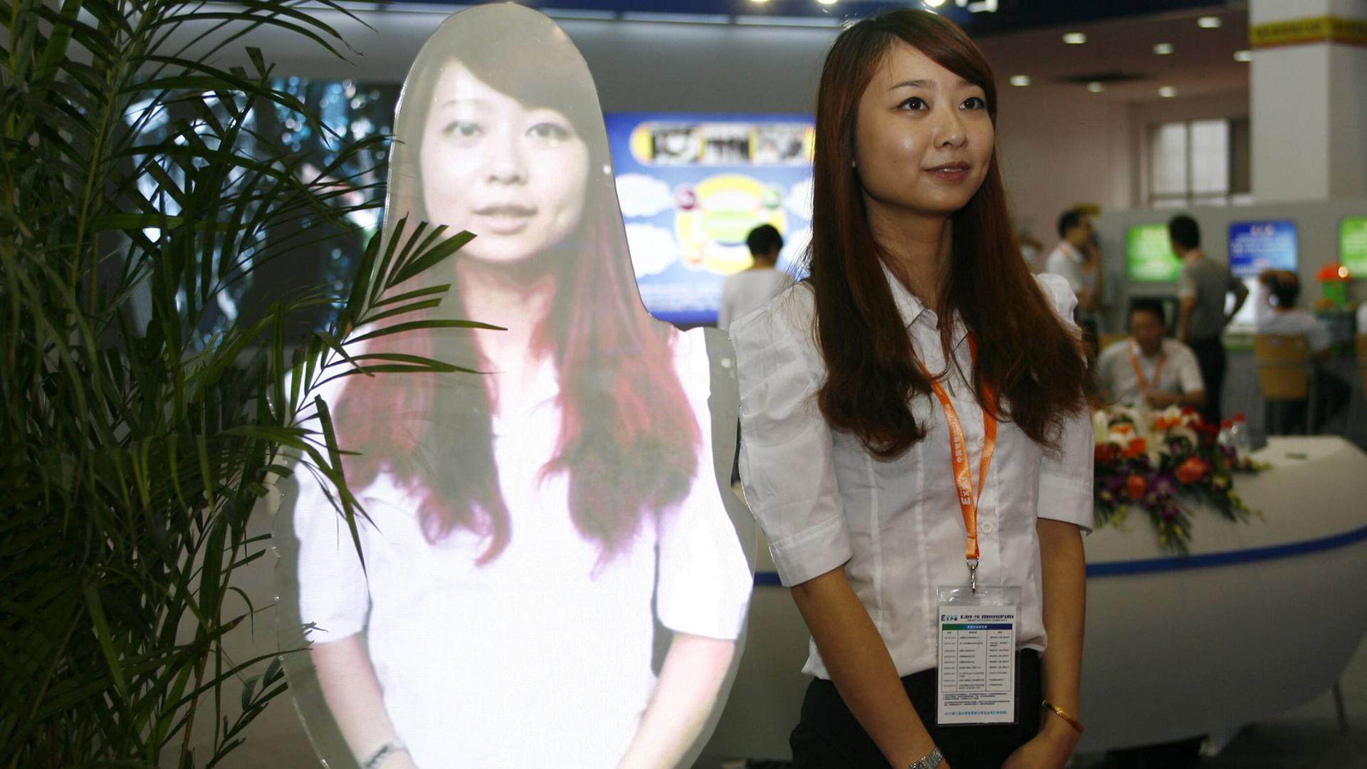 Eine Frau steht neben ihrem eigenen Hologramm auf der Smart City Expo in Ningbo City, China (2012) Eine Frau steht neben ihrem eigenen Hologramm auf der Smart City Expo in Ningbo City, China (2012)