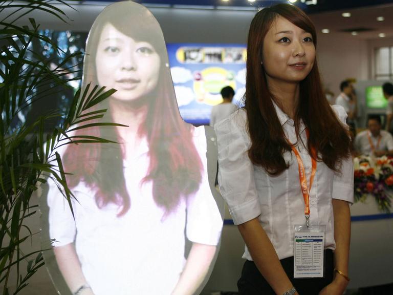 Eine Frau steht neben ihrem eigenen Hologramm auf der Smart City Expo in Ningbo City, China (2012)