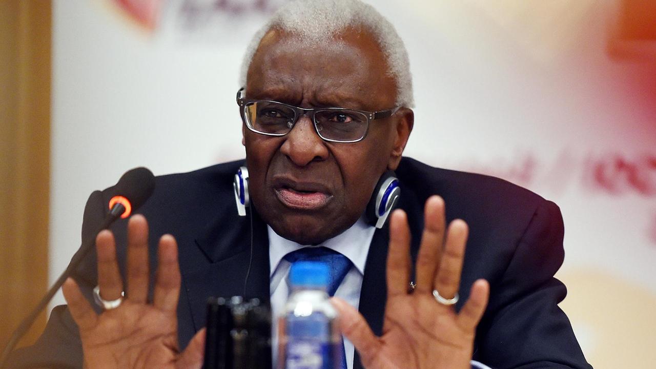 Diack sitzt vor einer weißen Wand mit roter Schrift vor einem Mikrofon und gestikuliert mit beiden Händen. Diack sitzt vor einer weißen Wand mit roter Schrift vor einem Mikrofon und gestikuliert mit beiden Händen.