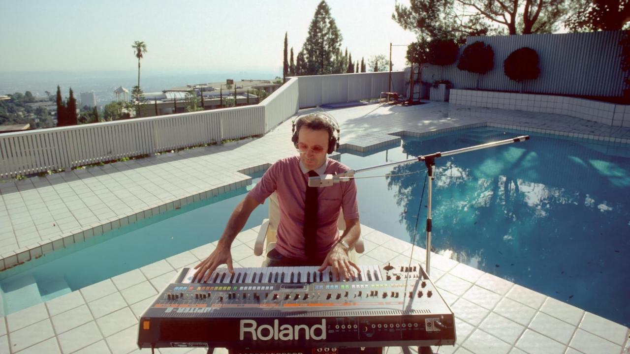 Giorgio Moroder sitzt an einem Pool und spielt auf einem Keyboard. Giorgio Moroder sitzt an einem Pool und spielt auf einem Keyboard.