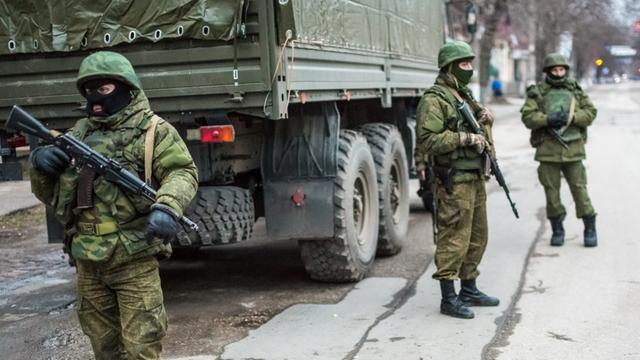 Bewaffnete Männer in Uniform stehen auf einer Straße von Simferopol