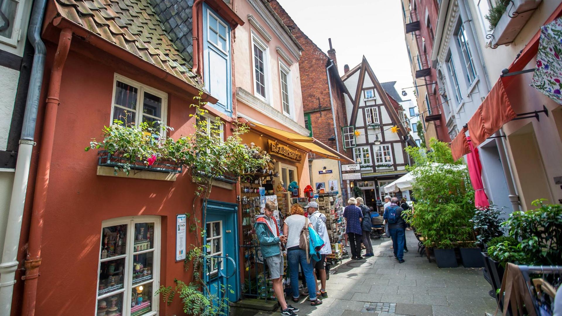 Das Schnoor-Viertel in der Bremer Altstadt zeichnet sich durch enge Gassen, kleine und bunte Häuser aus. Auf dem Bild stehen einige Menschen vor Schaufenstern. Das Schnoor-Viertel in der Bremer Altstadt zeichnet sich durch enge Gassen, kleine und bunte Häuser aus. Auf dem Bild stehen einige Menschen vor Schaufenstern.