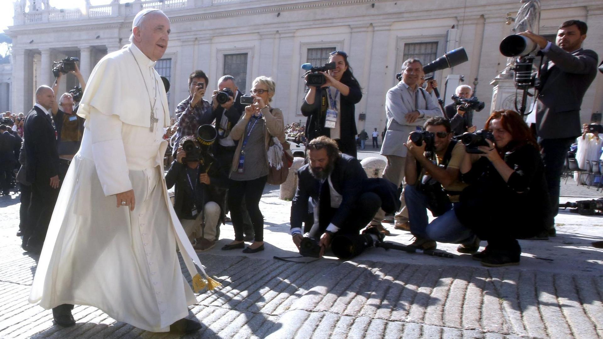 Papst Franziskus läuft an Journalisten mit Kameras vorbei. Papst Franziskus läuft an Journalisten mit Kameras vorbei.