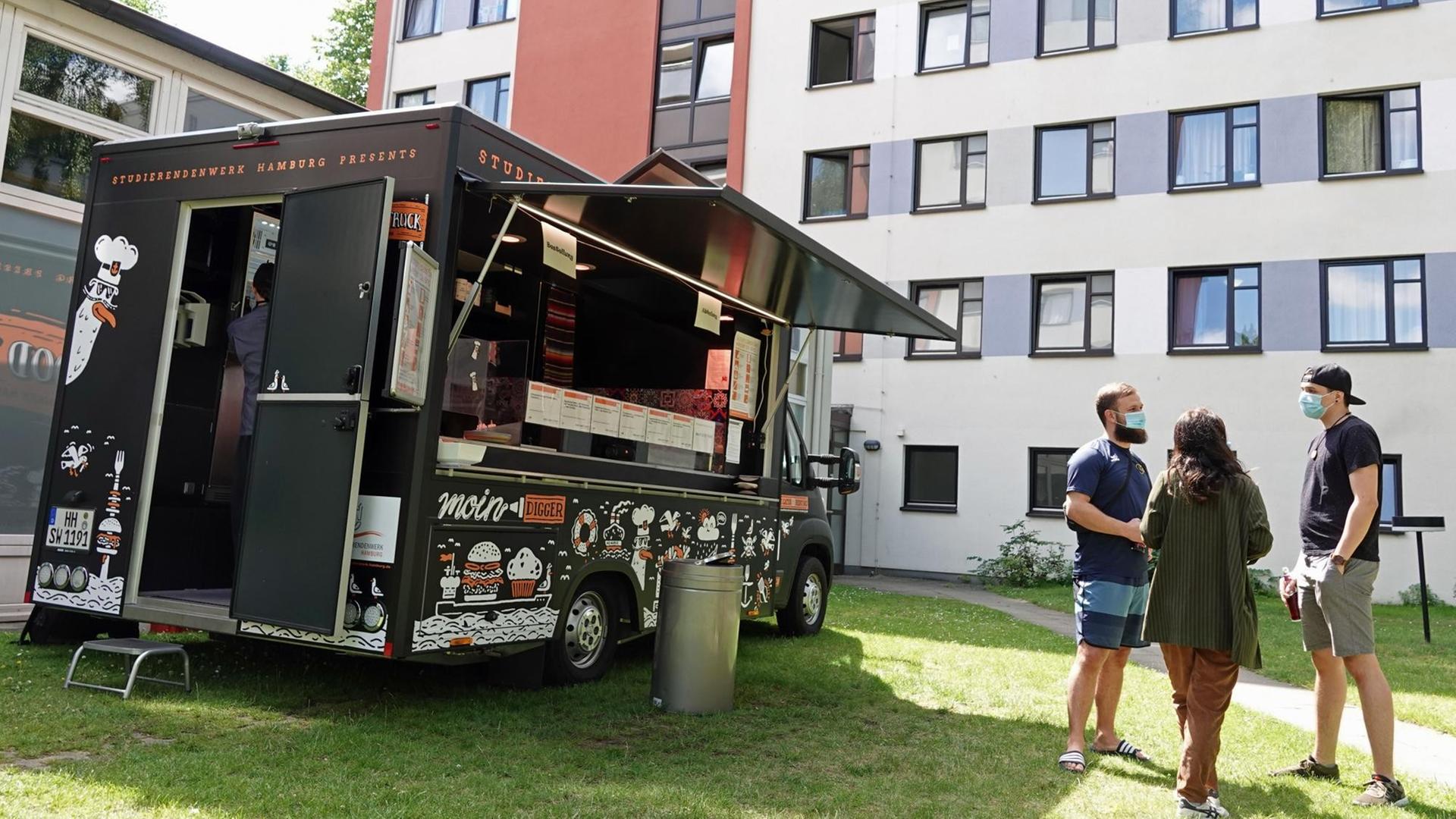 13.07.2020, Hamburg: Drei Studierende stehen vor dem Foodtruck des Hamburger Studierendenwerks in der Nähe des Margaretha-Rothe-Hauses. 13.07.2020, Hamburg: Drei Studierende stehen vor dem Foodtruck des Hamburger Studierendenwerks in der Nähe des Margaretha-Rothe-Hauses.