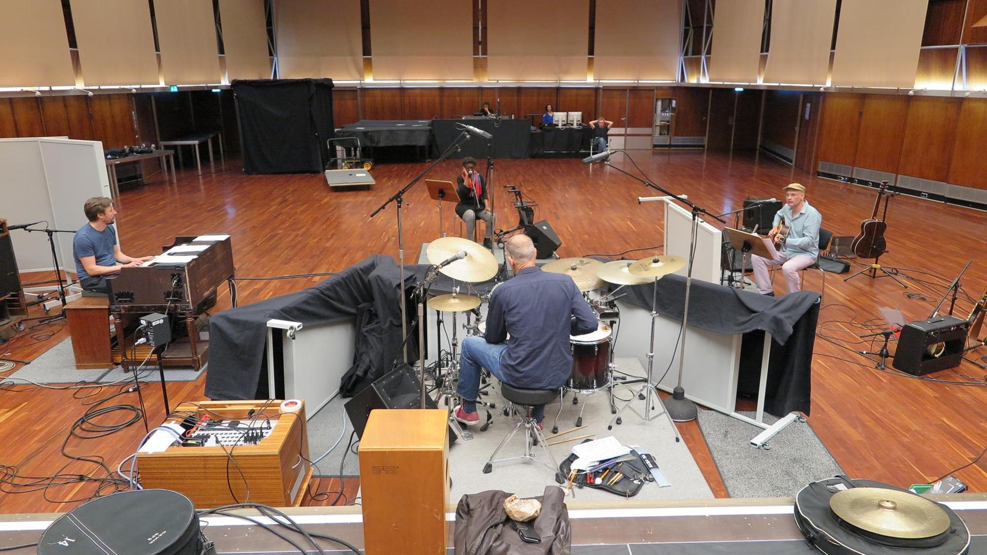Eine Sängerin und drei Männer sitzen im Kreis auf Stühlen hinter ihren Instrumenten Gitarre, Schlagzeug, Orgel in einem Konzertsaal. Eine Sängerin und drei Männer sitzen im Kreis auf Stühlen hinter ihren Instrumenten Gitarre, Schlagzeug, Orgel in einem Konzertsaal.