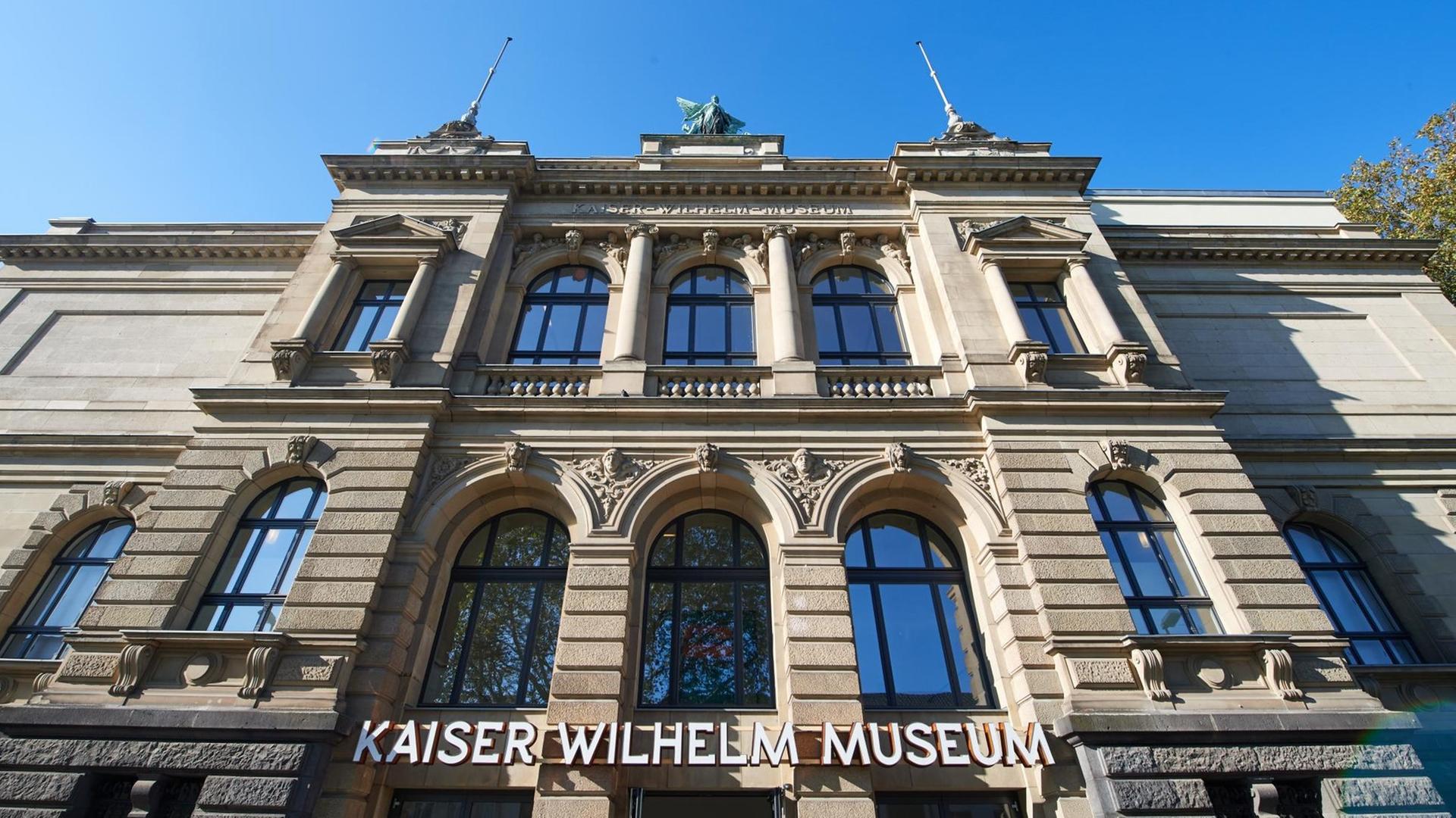 Die Fassade des Kaiser-Wilhelm-Museums in Krefeld mit Namenszug über dem Eingang aus der Froschperspektive.