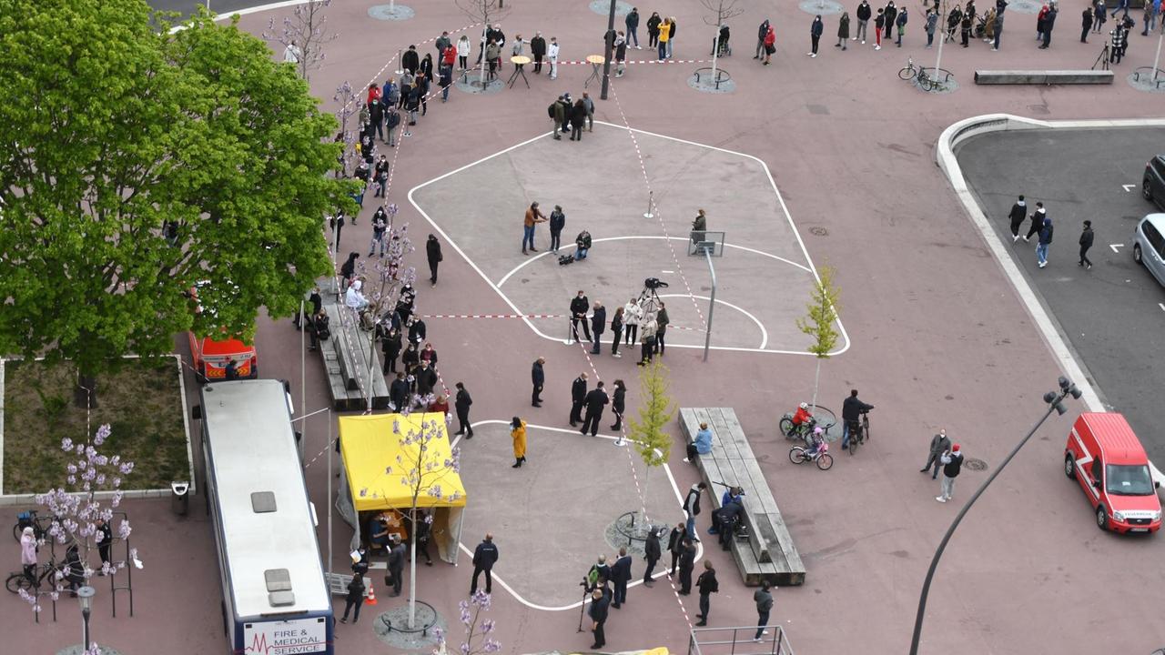 Menschen stehen im Kölner Stadtteil Chorweiler Schlange, um eine Corona-Impfung zu erhalten. Menschen stehen im Kölner Stadtteil Chorweiler Schlange, um eine Corona-Impfung zu erhalten.