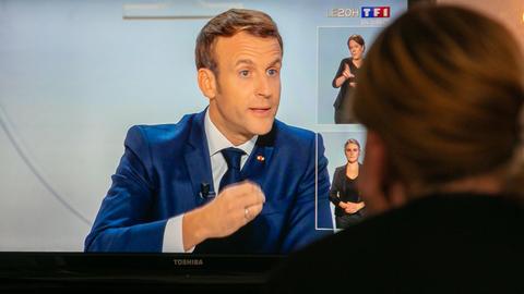 Eine Frau schaut die Fernsehansprache von Präsident Emmanuel Macron