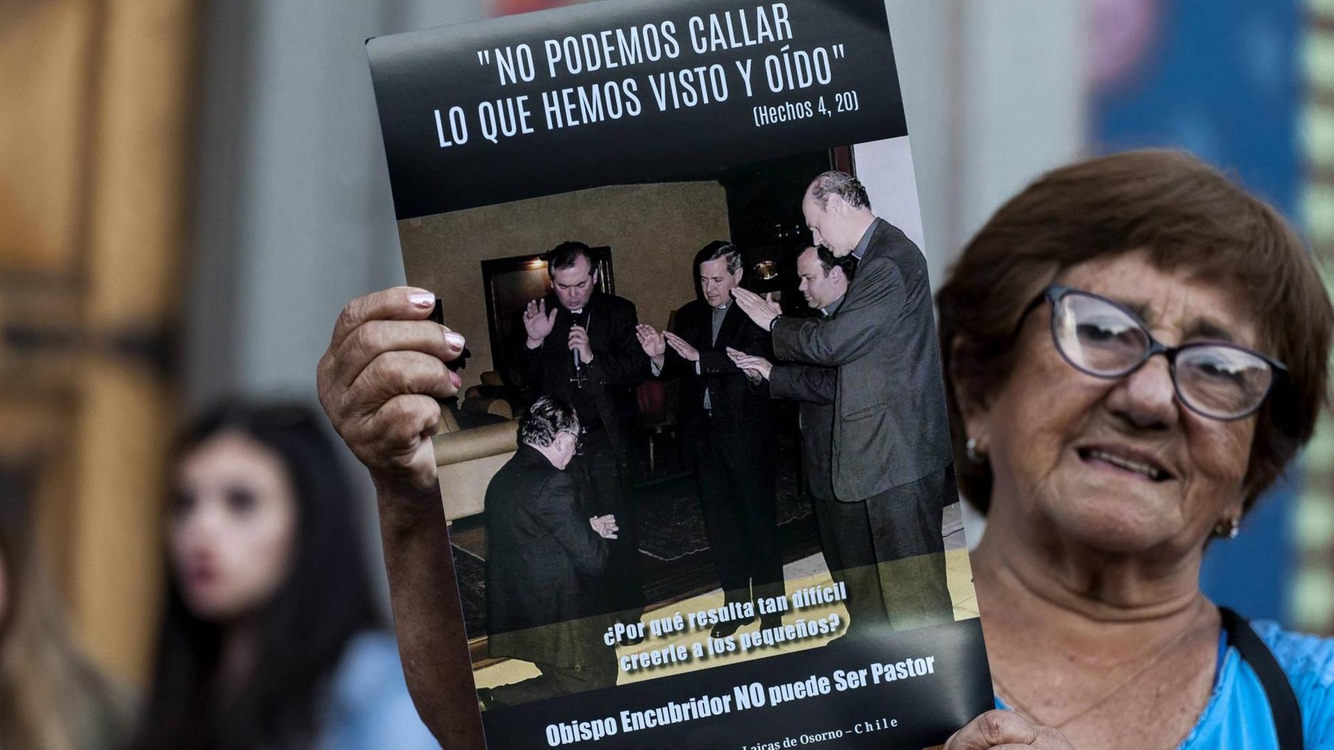 Eine Frau auf einer Demonstration am 24. Februar 2018 gegen den chilenischen Priesterausbilder Fernando Karadima. Auf dem Poster ist Karadima (l) zu sehen, als er von anderen Bischöfen (darunter auch Juan Barros, 3.v.r.) gesegnet wird. Darüber steht ein Vers aus aus der Apostelgeschichte: "Wir können unmöglich schweigen über das, was wir gesehen und gehört haben" Eine Frau auf einer Demonstration am 24. Februar 2018 gegen den chilenischen Priesterausbilder Fernando Karadima. Auf dem Poster ist Karadima (l) zu sehen, als er von anderen Bischöfen (darunter auch Juan Barros, 3.v.r.) gesegnet wird. Darüber steht ein Vers aus aus der Apostelgeschichte: "Wir können unmöglich schweigen über das, was wir gesehen und gehört haben"