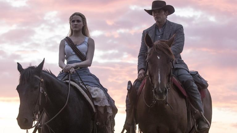 Evan Rachel Wood und James Marsden reiten auf Pferden vor dem Hintergrund eines Sonnenuntergangs. Evan Rachel Wood und James Marsden reiten auf Pferden vor dem Hintergrund eines Sonnenuntergangs.