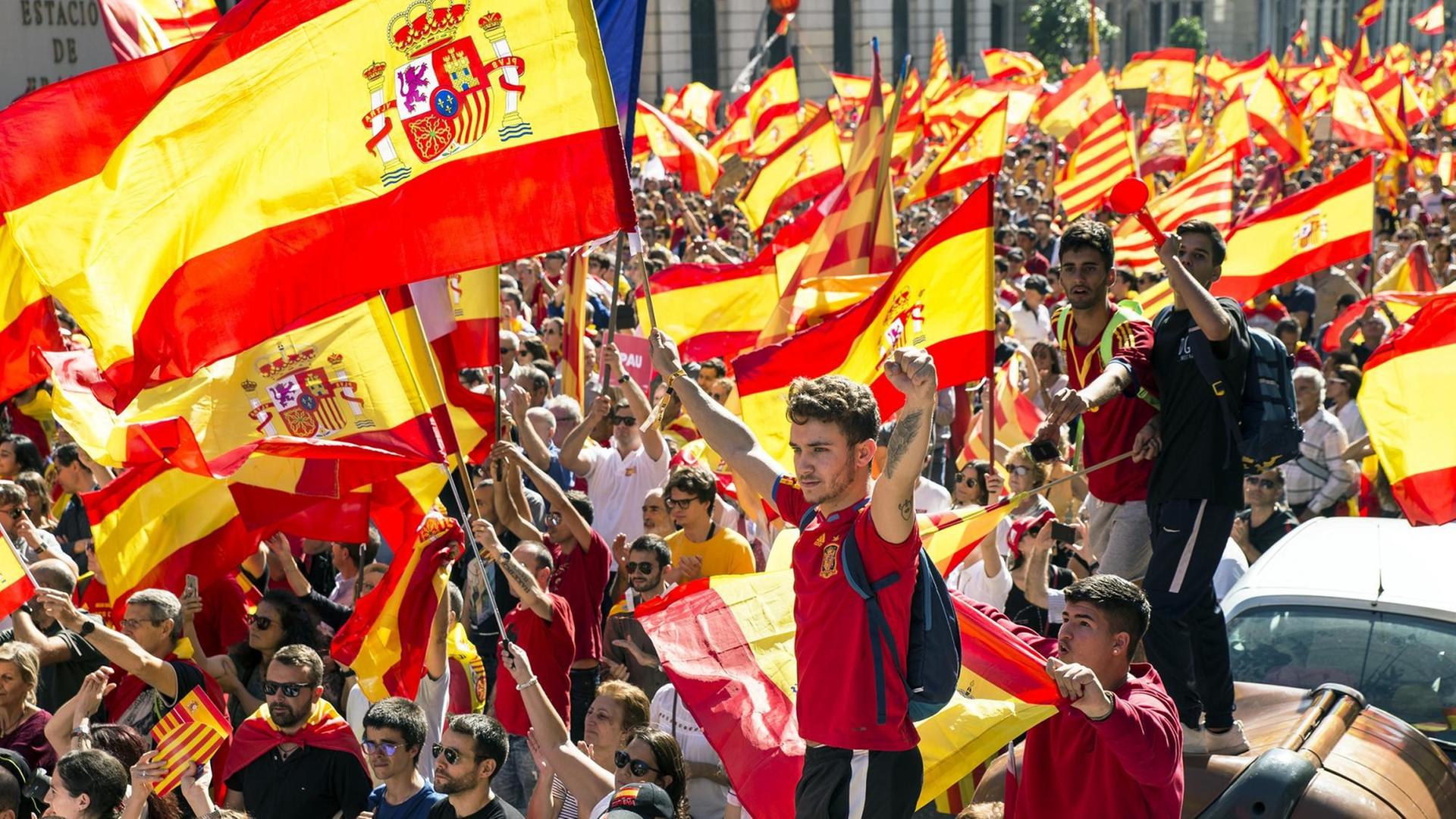In einer Menschenmenge werden spanische Flaggen geschwenkt. In einer Menschenmenge werden spanische Flaggen geschwenkt.
