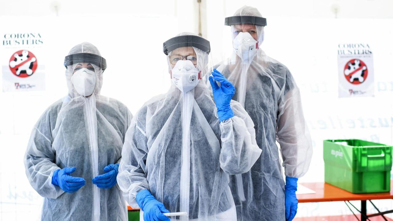 Drei Mitarbeiter vom Gesundheitsamt in Berlin Mitte stehen in Schutzkleidung, in der ambulanten Corona-Test- Einrichtung. Drei Mitarbeiter vom Gesundheitsamt in Berlin Mitte stehen in Schutzkleidung, in der ambulanten Corona-Test- Einrichtung.