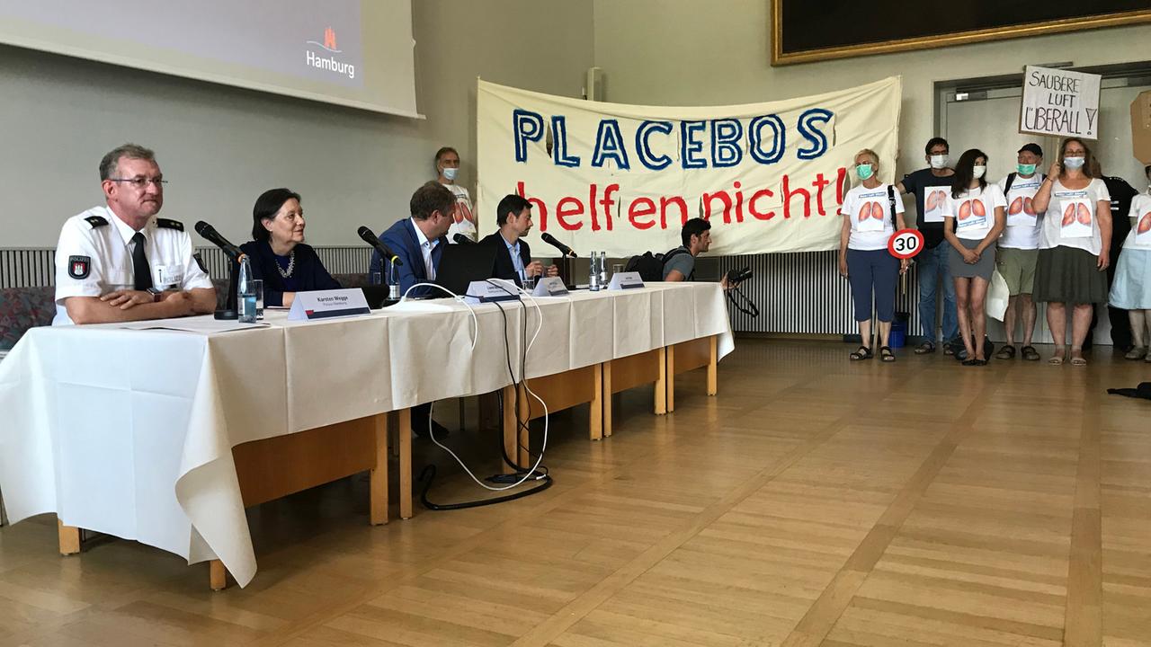 Umweltschützer protestieren bei einer offiziellen Veranstaltung mit Plakaten wie "Placebos helfen nicht" gegen die Einführung der ihrer Ansicht nach viel zu eng begrenzten Fahrverbotszonen in Hamburg.