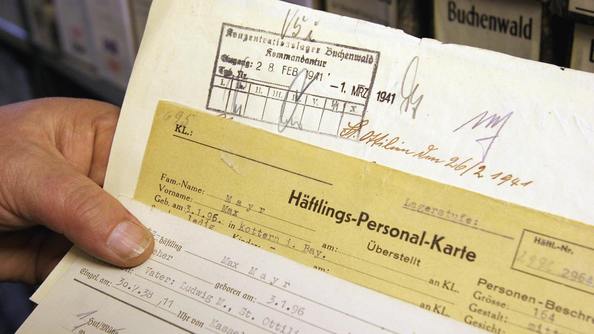 Eine Hand hält in den Räumen des Internationalen Suchdienstes des Roten Kreuzes (ITS) im nordhessischen Bad Arolsen Häftlingskarten und weitere Dokumente eines Zwangsarbeiters (Archivbild vom 25.11.2004). Um die oft erschütternden Dokumente für die kommenden Generationen zu erhalten, hat die Restaurierung der vom Verfall bedrohten Akten begonnen. Der ITS verwaltet 47 Millionen Dokumente mit Hinweisen auf 17 Millionen Opfer des NS-Regimes. Jährlich sollen in einer Spezialmaschine rund 200 000 Dokumente entsäuert und entlaminiert werden, sagt ITS-Archivverwalter Udo Joos. Foto: Uwe Zucchi dpa/lhe (zu lhe Korr-Bericht "Kriegspapier zerfällt: Zwangsarbeiter-Archiv wird restauriert" vom 13.12.) +++(c) dpa - Report+++ Eine Hand hält in den Räumen des Internationalen Suchdienstes des Roten Kreuzes (ITS) im nordhessischen Bad Arolsen Häftlingskarten und weitere Dokumente eines Zwangsarbeiters (Archivbild vom 25.11.2004). Um die oft erschütternden Dokumente für die kommenden Generationen zu erhalten, hat die Restaurierung der vom Verfall bedrohten Akten begonnen. Der ITS verwaltet 47 Millionen Dokumente mit Hinweisen auf 17 Millionen Opfer des NS-Regimes. Jährlich sollen in einer Spezialmaschine rund 200 000 Dokumente entsäuert und entlaminiert werden, sagt ITS-Archivverwalter Udo Joos. Foto: Uwe Zucchi dpa/lhe (zu lhe Korr-Bericht "Kriegspapier zerfällt: Zwangsarbeiter-Archiv wird restauriert" vom 13.12.) +++(c) dpa - Report+++