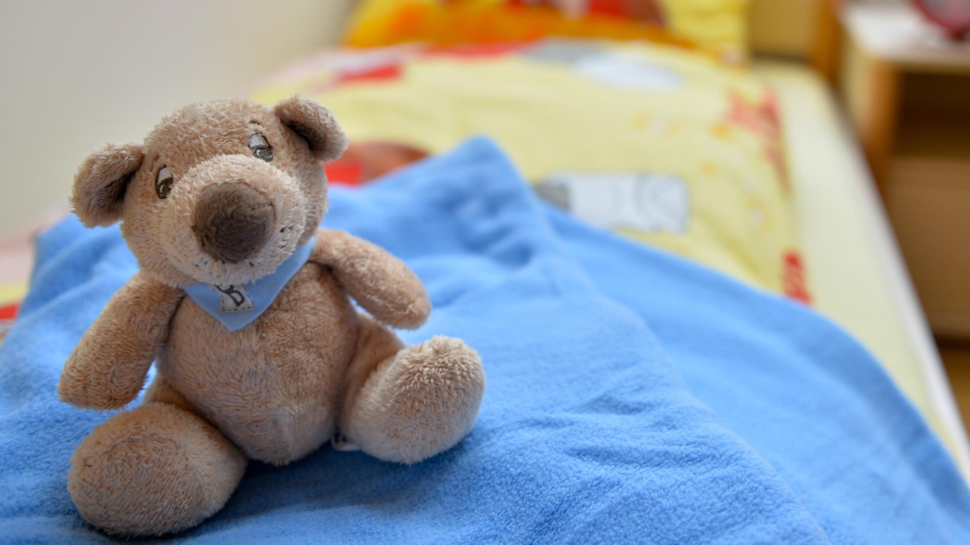 Ein Stofftier sitzt in einem Kinderzimmer auf einem Bett.