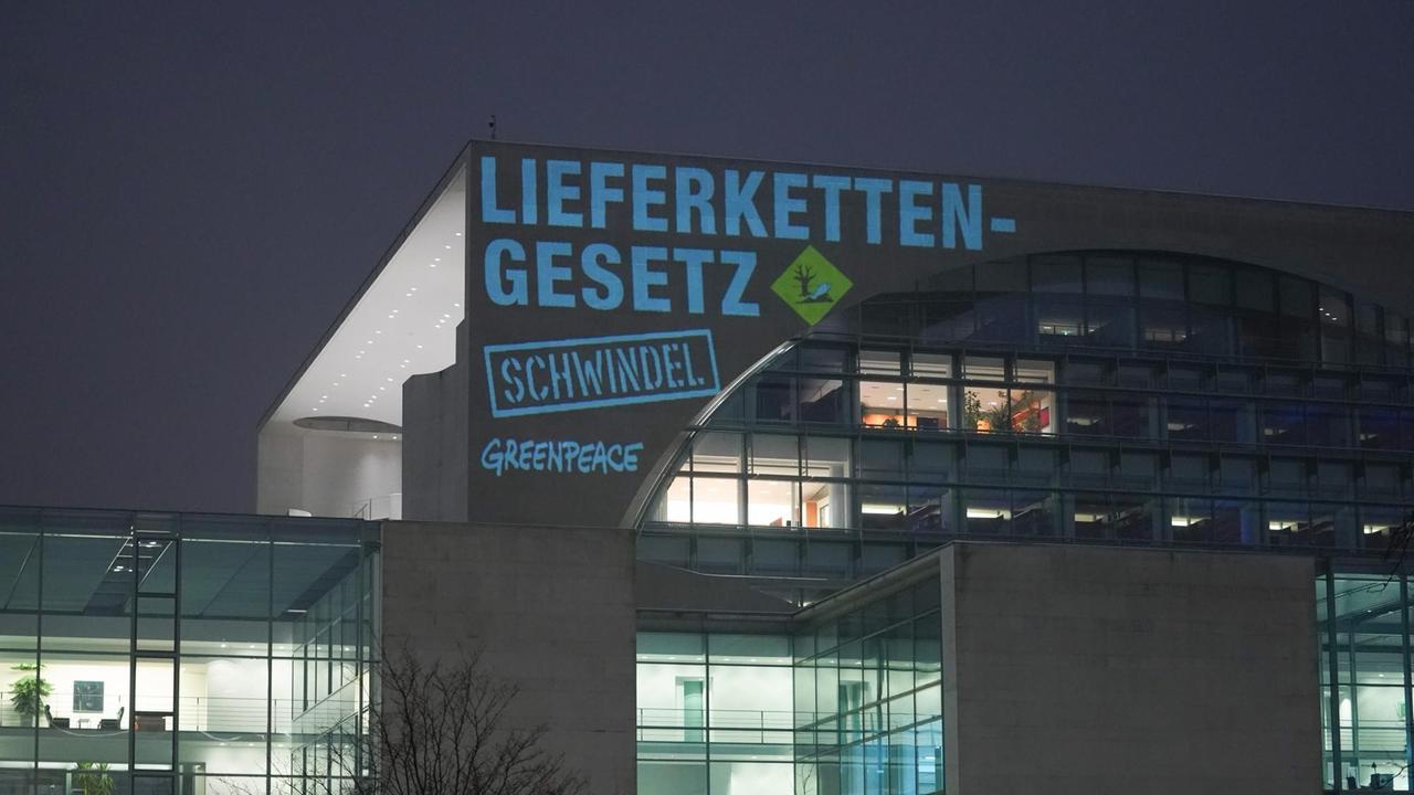 Bei einer Greenpeace-Aktion zum Lieferkettengesetz wird am frühen Morgen der Spruch "Lieferkettengesetz. Schwindel" an die Außenfassade des Bundeskanzleramts projiziert.