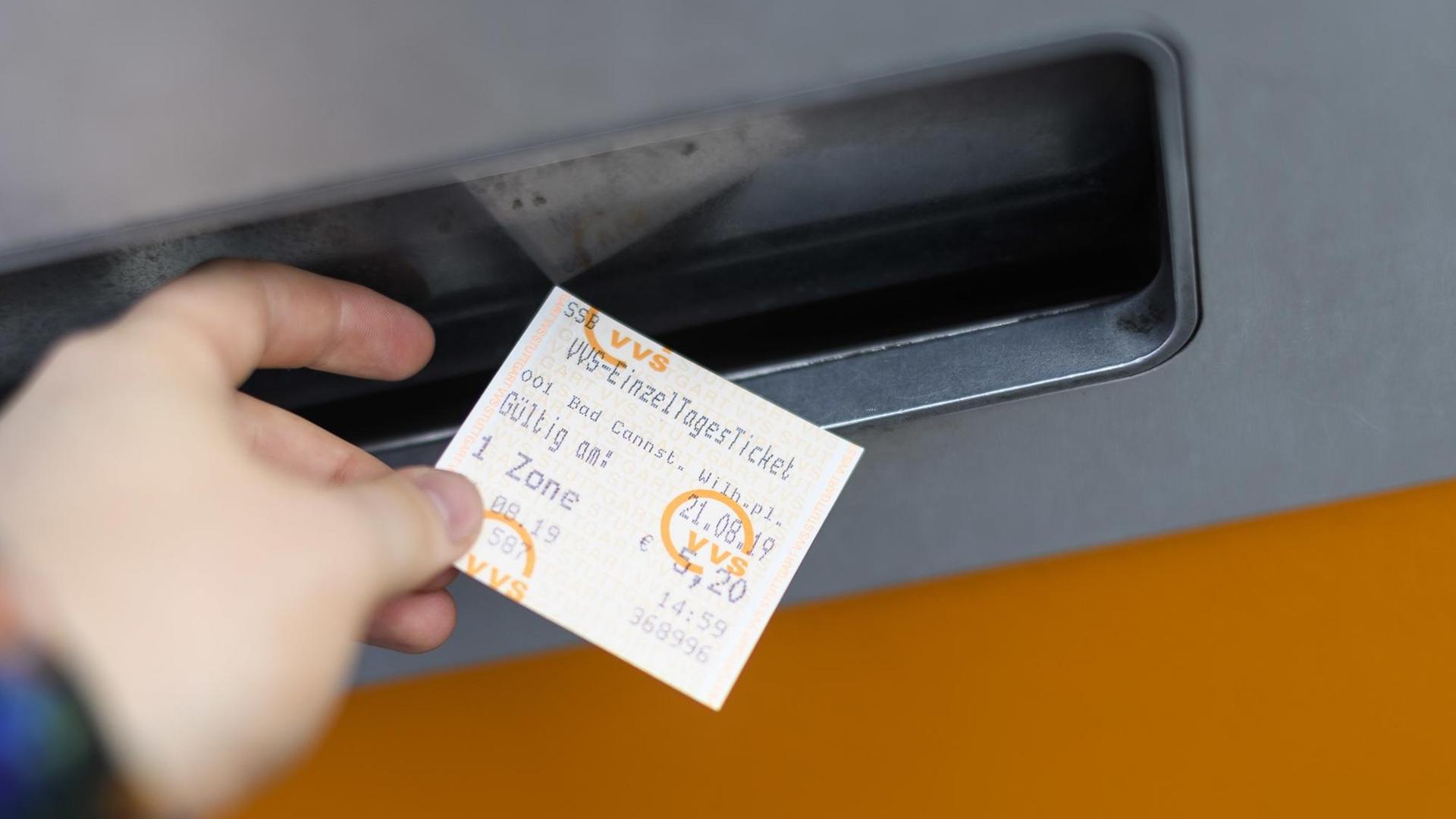 Eine Hand nimmt ein VVS Einzel Tagesticket aus einem Ticketautomat in Stuttgart. Eine Hand nimmt ein VVS Einzel Tagesticket aus einem Ticketautomat in Stuttgart.