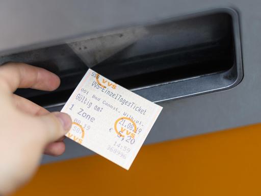 Eine Hand nimmt ein VVS Einzel Tagesticket aus einem Ticketautomat in Stuttgart.
