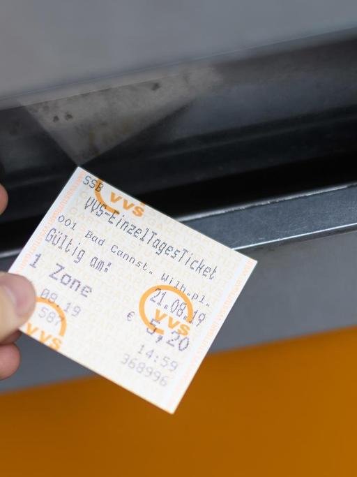 Eine Hand nimmt ein VVS Einzel Tagesticket aus einem Ticketautomat in Stuttgart.