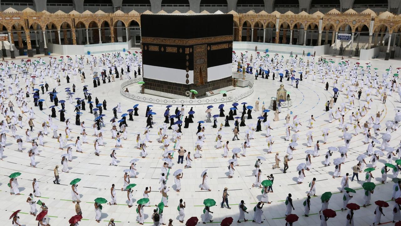 Menschen gehen mit großem Abstand zueinander um die Kaaba in der Großen Moschee von Mekka herum Menschen gehen mit großem Abstand zueinander um die Kaaba in der Großen Moschee von Mekka herum