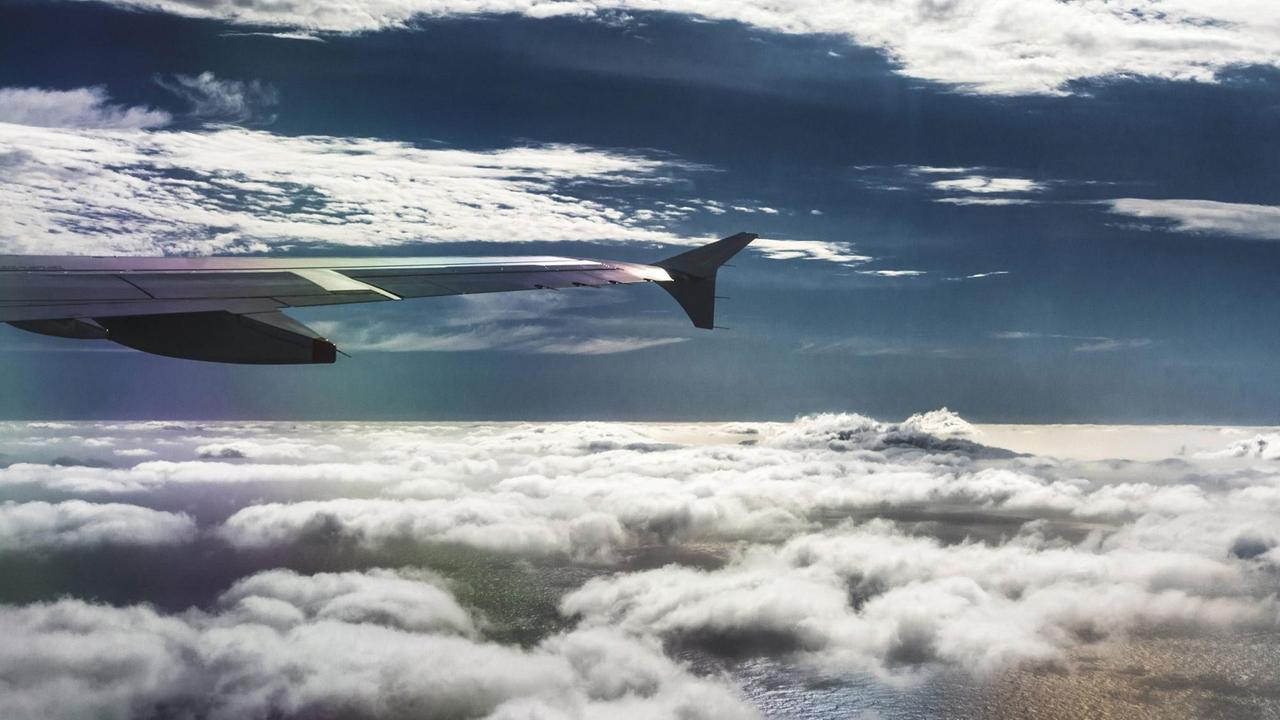 Ausblick aus dem Flugzeugfenster beim Flug über den Wolken mit leichten Turbulenz.