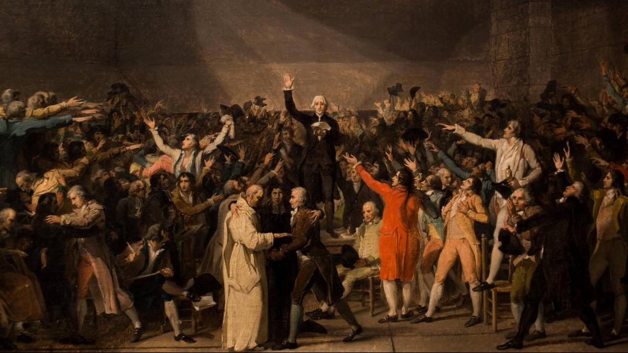 In einer Turnhalle stehen viele Menschen, in der Mitte ein Mann mit der Schwurhand erhoben auf einem Tisch. Die Menschen jubeln ihm zu und umarmen sich. In einer Turnhalle stehen viele Menschen, in der Mitte ein Mann mit der Schwurhand erhoben auf einem Tisch. Die Menschen jubeln ihm zu und umarmen sich.