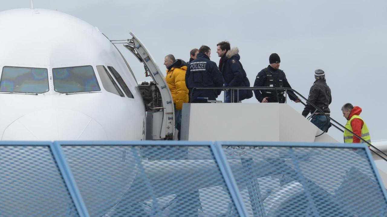 Das Bild zeigt, wie die Flüchtlinge von der Gangway in die weiße Maschine steigen. Zwei Polizisten überwachen das Ganze. Das Bild zeigt, wie die Flüchtlinge von der Gangway in die weiße Maschine steigen. Zwei Polizisten überwachen das Ganze.