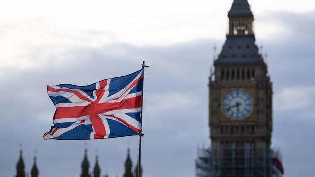 Eine Fahne vom Vereinigtem Königreich (Union Jack) weht am in London (Großbritannien) im Wind. Im Hintergrund ist der Uhrturm Elizabeth Tower mit dem Big Ben zu sehen.