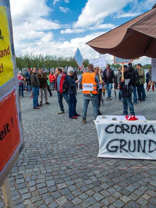 01.05.2020, Mecklenburg-Vorpommern, Schwerin: Ein Schild mit der Aufschrift «Wo Recht zu Unrecht wird, wird Widerstand zur Pflicht. Freiheit." (l) und ein Banner "Coronapanik frisst Grundgesetz" (r) sind bei der Mahnwache zu sehen, zu der sich am Pfaffenteich mehrere hundert Bürger versammeln und gegen die Corona-Schutzmaßnahmen protestieren. Nach Aufforderungen der Polizei wurde das Treffen aufgelöst. Foto: Jens Büttner/dpa-Zentralbild/dpa | Verwendung weltweit