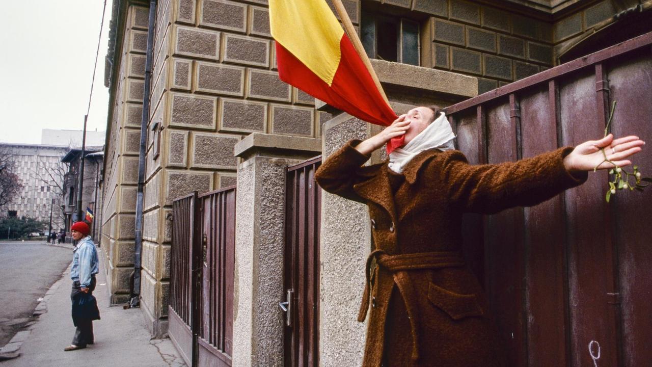 Eine Frau betet für die Befreiung Rumäniens aus der Diktatur - sie küsst die Flagge des Landes, aufgenommen im Dezember 1989.