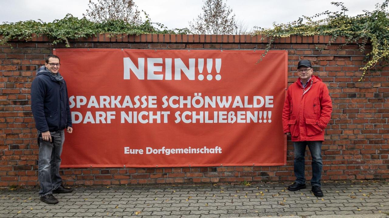 Grünen-Politiker Benjamin Raschke (links) und Bürgermeister Roland Gefreiter vor einem Plakat mit der Aufschrift: "Sparkasse Schönwalde darf nicht schließen" Grünen-Politiker Benjamin Raschke (links) und Bürgermeister Roland Gefreiter vor einem Plakat mit der Aufschrift: "Sparkasse Schönwalde darf nicht schließen"
