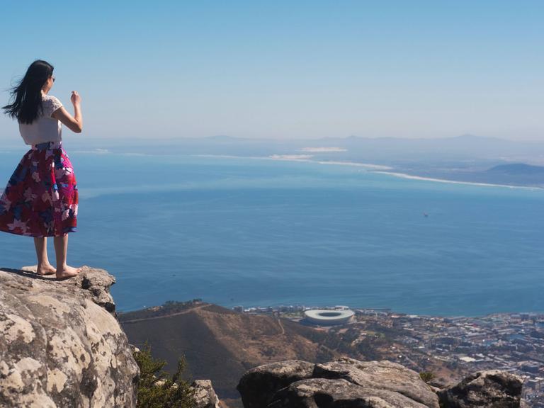 Eine Frau steht auf einem Berg und blickt auf Kapstadt.