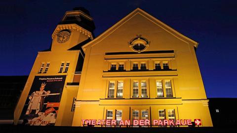 Beleuchtete Fassade und der rote Schriftzug des Theaters an der Parkaue