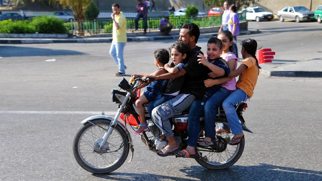 Straßenszene in Kairo: Ein Vater fährt mit seinen fünf Kindern auf dem Motorrad Straßenszene in Kairo: Ein Vater fährt mit seinen fünf Kindern auf dem Motorrad