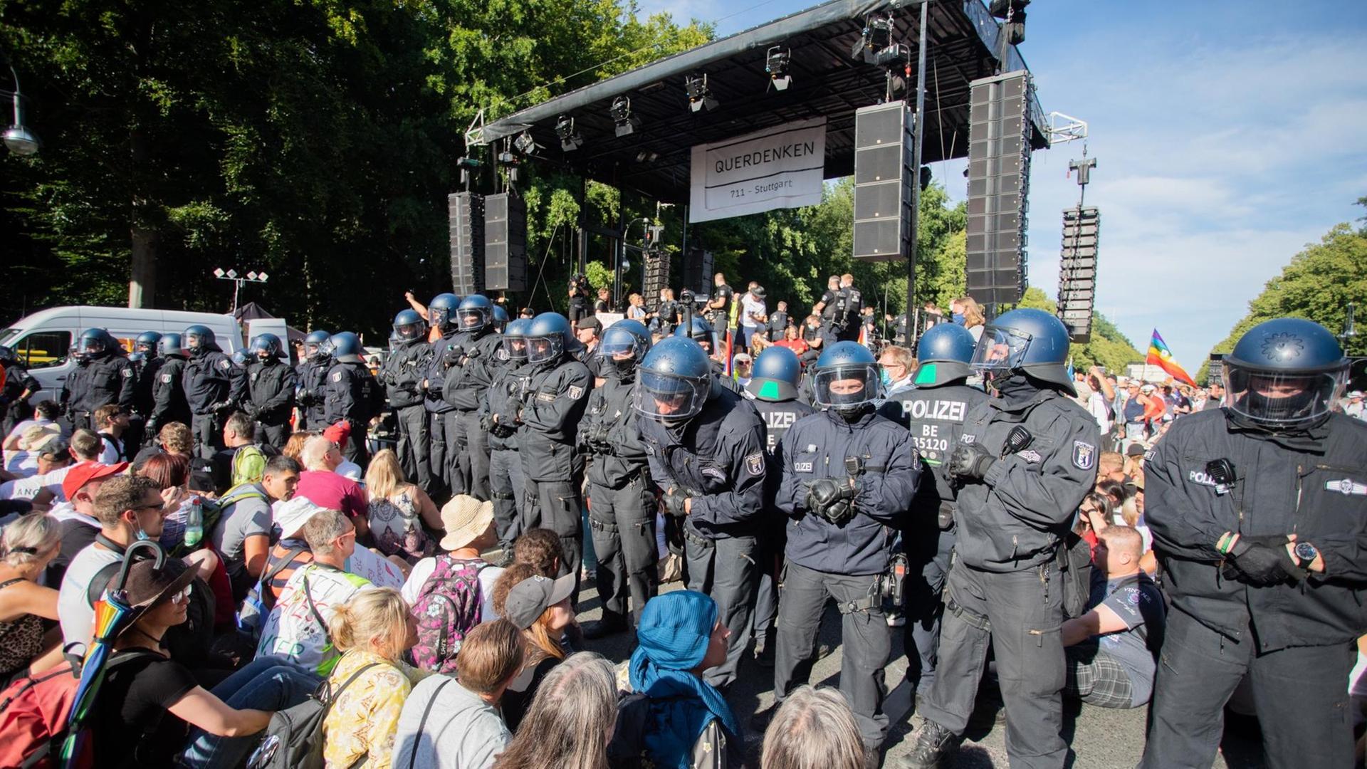 Polizisten stehen bei einer Kundgebung gegen die Corona-Beschränkungen auf der Straße des 17. Juni zwischen Teilnehmern vor einer Bühne. Polizisten stehen bei einer Kundgebung gegen die Corona-Beschränkungen auf der Straße des 17. Juni zwischen Teilnehmern vor einer Bühne.