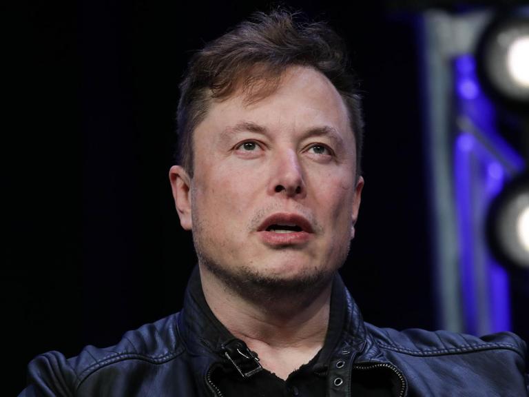Oberkörperporträt von Elon Musk. Er trägt ein schwarze Jacke und darunter ein ebenfalls schwarzes Oberteil.