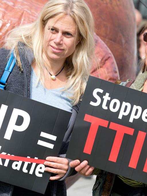 Zwei Frauen protestieren am 06.05.2014 vor dem Brandenburger Tor in Berlin gegen das Freihandelsabkommen TTIP zwischen der EU und den USA mit Transparenten.